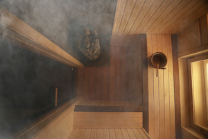 A wooden sauna room with warm, glowing wood panels. Steam is rising gently from a heated area, creating a cozy atmosphere.