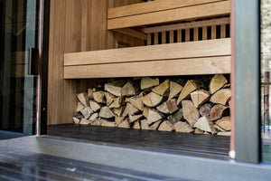 A cozy indoor sauna with wooden benches, soft lighting and a glass door, exuding warmth and relaxation.