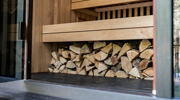 A cozy indoor sauna with wooden benches, soft lighting and a glass door, exuding warmth and relaxation.