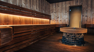 An infrared sauna with sleek wooden panels and infrared heaters embedded in walls, emitting a gentle, warm glow. The sauna features comfortable seating and a serene, modern design