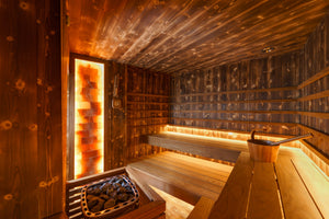 A wooden sauna room with benches along the walls and soft lighting, creating a warm, cozy atmosphere.