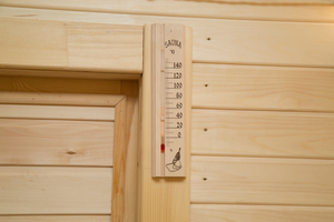 Thermometer displaying a temperature of 65 degrees celsius inside a wooden sauna. 