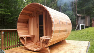 Wooden barrel sauna on a wooden deck with a forest background