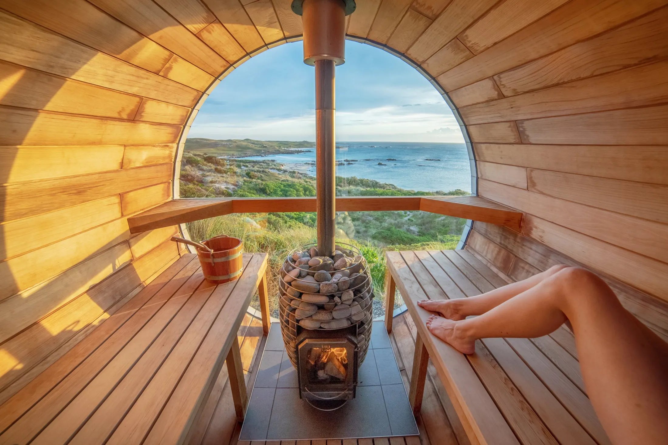Person relaxing in a wooden sauna with a scenic view outside