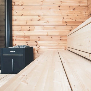 Harvia stove in a wooden sauna with a wooden bench by Finnish Sauna Builders