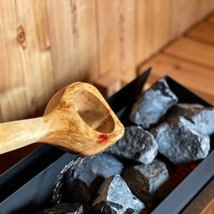 Homecraft H-Series Electric Sauna Heater Wooden spoon over hot stones in a sauna setting